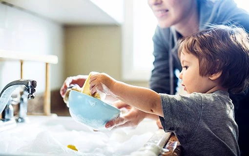 female and young boy washing up bowl