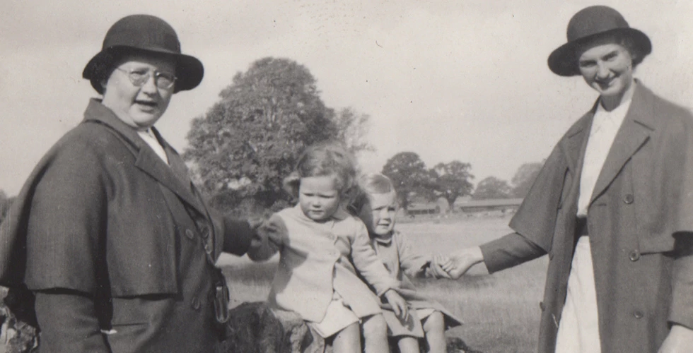 two female Norland nannies holding hands of two children on wall in 1900s
