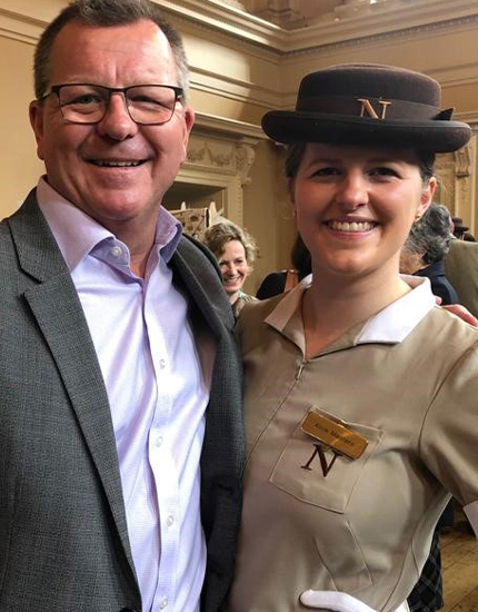 female in Norland nanny uniform standing with a man in a suit