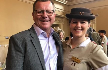 female in Norland nanny uniform standing with a man in a suit
