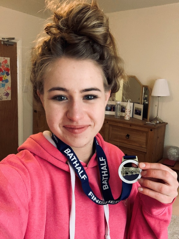 girl holding medal after running a marathon