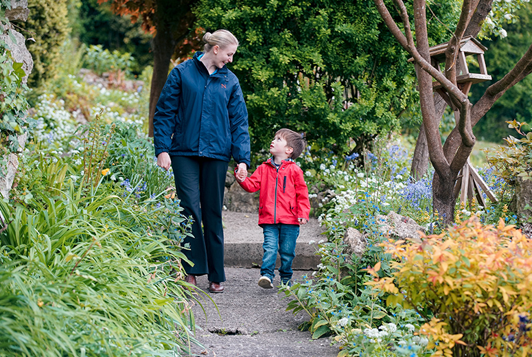 female student and young boy holding hands and talking in garden
