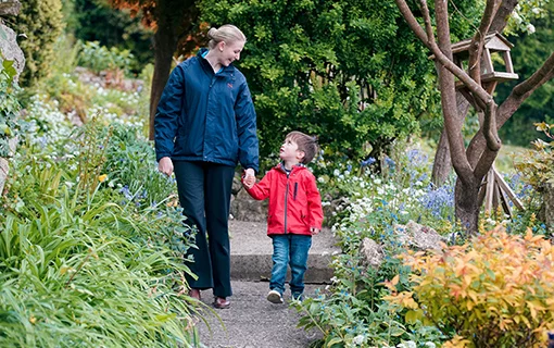 female student and young boy holding hands and talking in garden