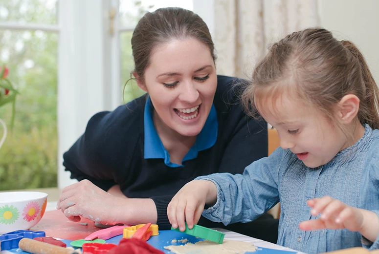 female nanny and young girl playing with salt dough and stencils