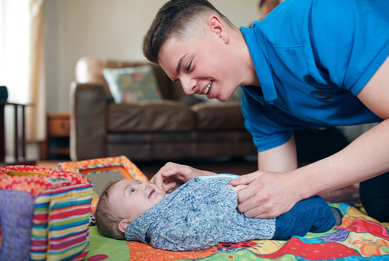 male student looking after baby boy on mat