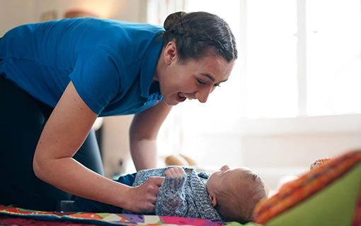 female student playing with baby on mat