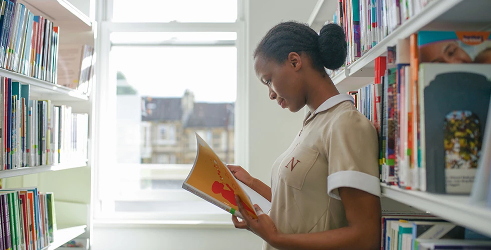 female student looking at text book in library
