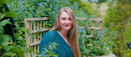 a female sat in a garden smiling