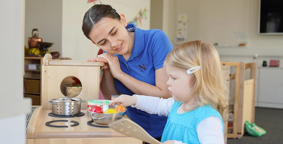 female and young girl playing with kitchen set in a nursery setting
