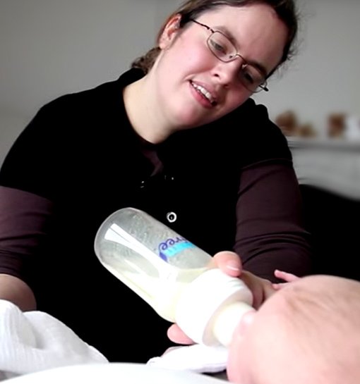 female nanny feeding two babies from bottle