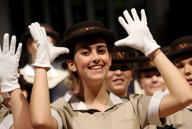 female Norland nanny in uniform wearing white gloves communicating via Makaton which is taught via the value added curriculum