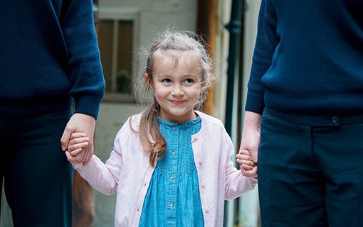 image of a girl smiling holding two adults hands