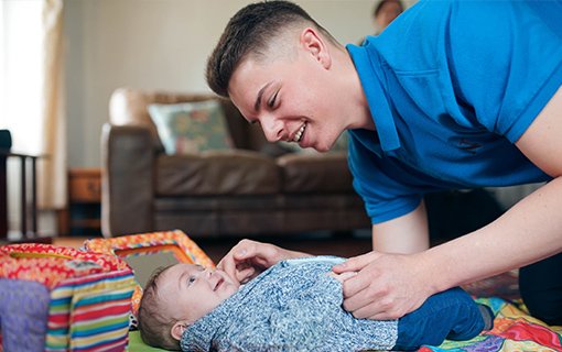 male student looking after baby boy on mat