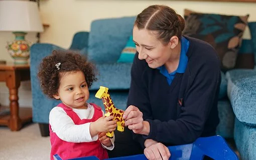 a little girl holding a toy giraffe