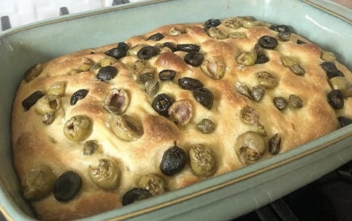 a tray of sourdough focaccia that has just come out of the oven