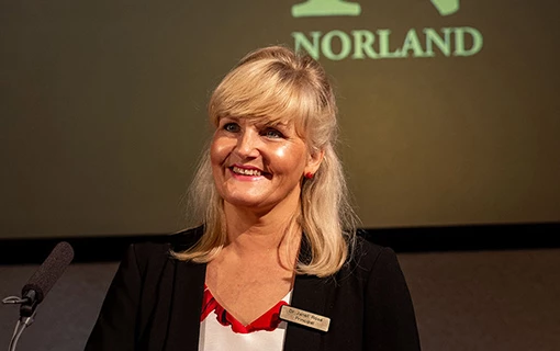 A female stood at a podium talking into a microphone