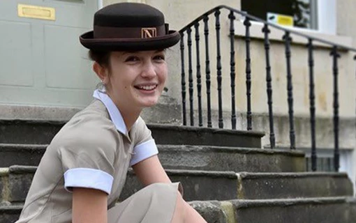 a female student sat on some steps smiling