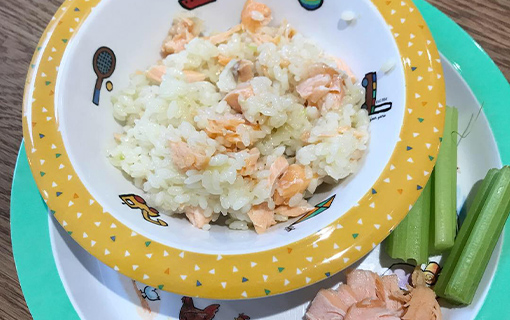 a bowl of children's food with some cucumber on the side of the plate