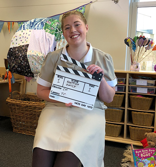 a female student holding a clapper board on a film set