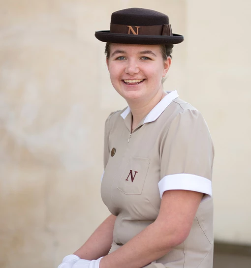 a female student sat on a wall smiling