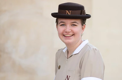 a female student studying to become an early years practitioner sat on a wall smiling