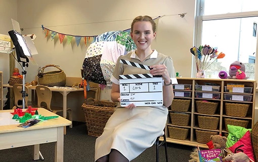 a female in a nursery holding a clapper board