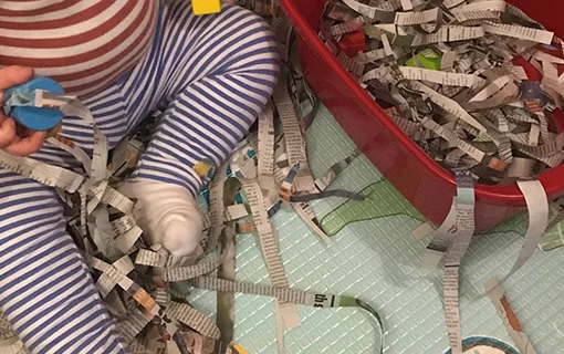 a child playing with shredded newspaper