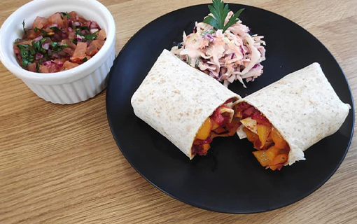a plate with fajitas, coleslaw and salsa made by a student