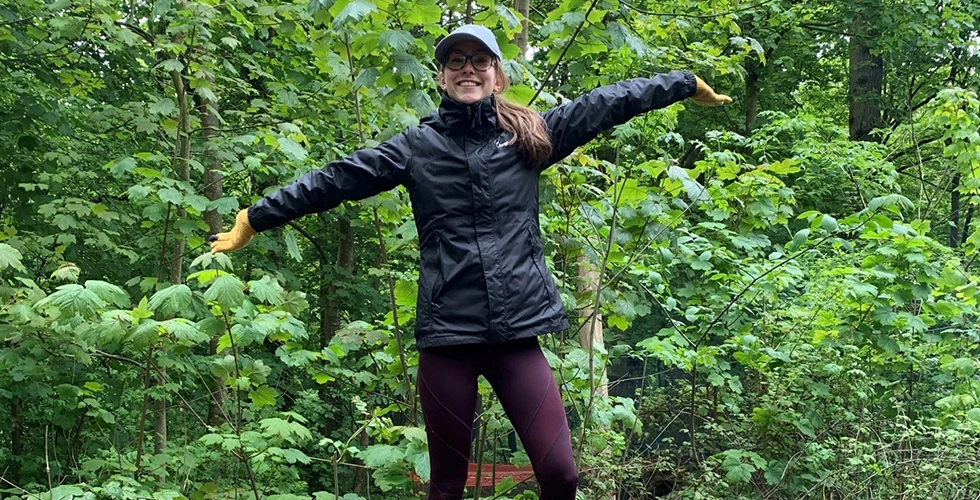 a female stood on a tree trunk smiling