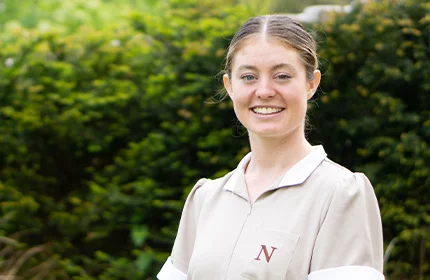 a female international norland student who is studying an early years degree in her uniform smiling