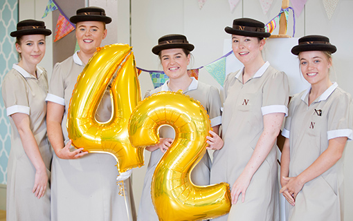 students in their formal dress holding balloons that say 42