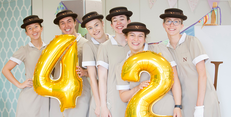 students in their formal dress holding balloons that say 42