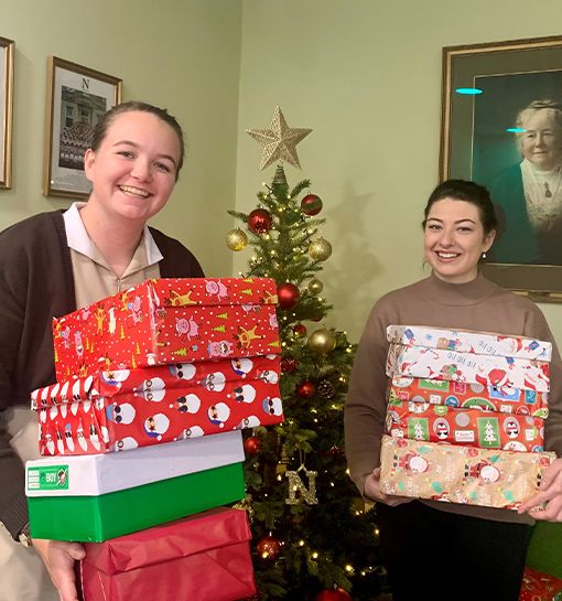 Two students holding shoeboxes being donated to charity