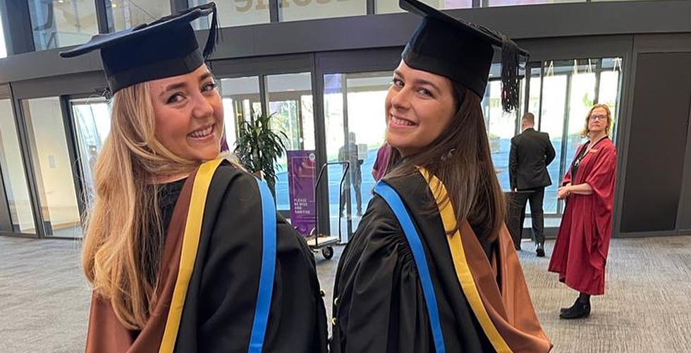 two female graduates smiling
