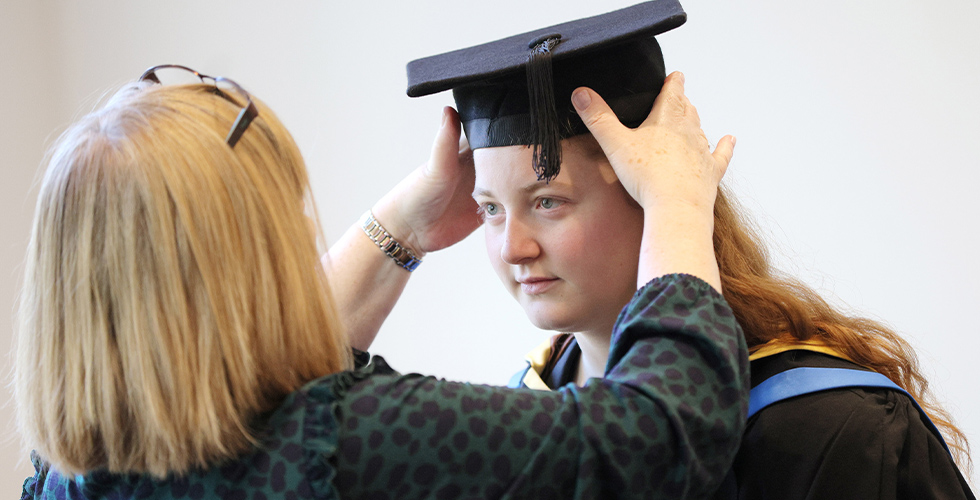 a graduate having her mortar board adjusted