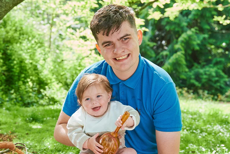 a male Norland Nanny student holding a baby