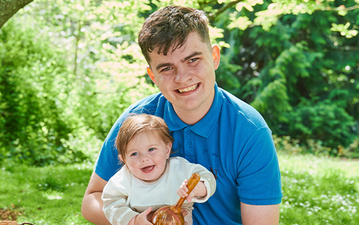 a male Norland Nanny student holding a smiling baby