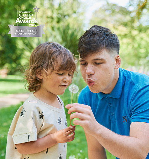 a male nanny and child blowing a flower