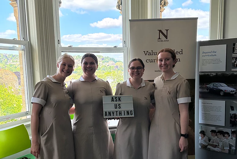 Four Norland Nanny students holding a light box saying 'Ask us anything'