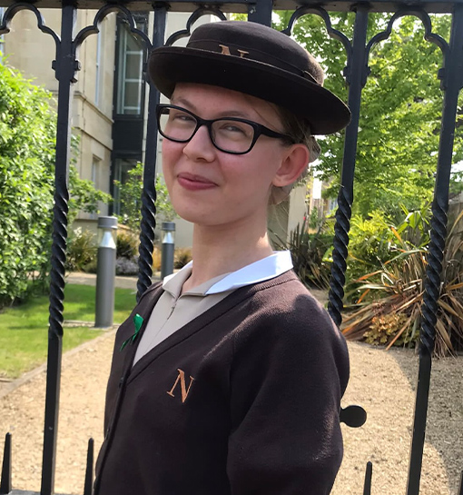 a female Norland Nanny student smiling outside the gates at the Oldfield Park campus in Bath, UK