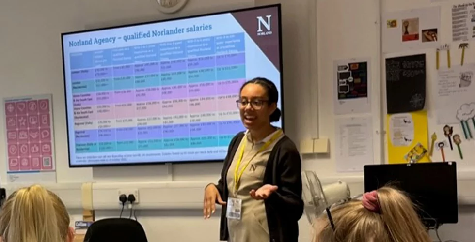 A female student training to become a Norland Nanny delivering a presentation in a classroom in front of an electronic board.