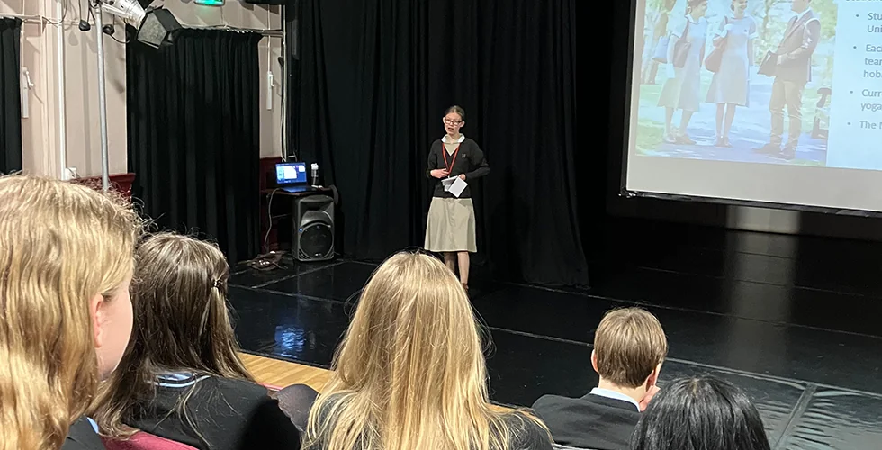 A Norland Nanny student stood presenting to a group of students with a screen behind her