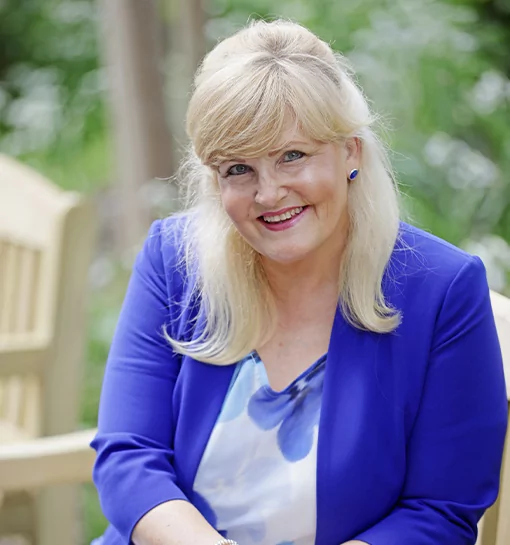 Dr Janet Rose, Principal at Norland, sat on a garden bench smiling