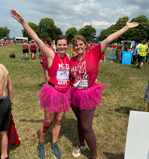 Two females in pink clothing smiling after completing a charity event for Cancer Research UK.