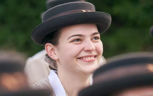 Sophia, a Norland Nanny student, stood smiling in her formal uniform looking upwards