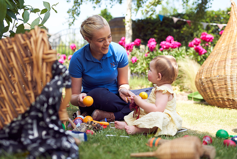 A female Norland Nanny student playing with a child in a garden