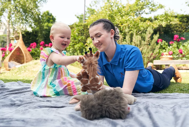 A female Norland Nanny student playing with a puppet with a child