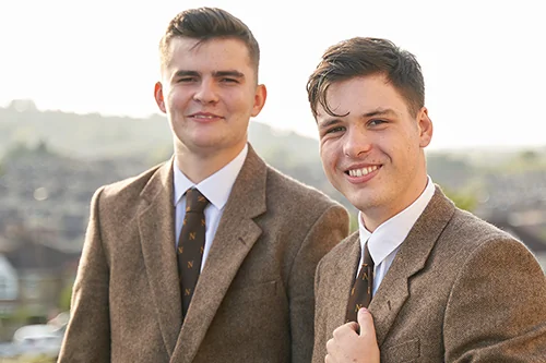 Two male Norland Nanny students in their uniform.