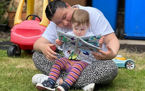 Norland student and child reading together in a garden