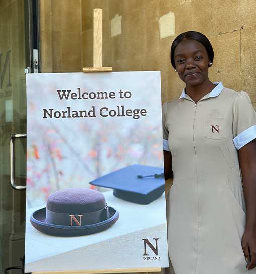 Norland student in formal uniform standing by college open day sign